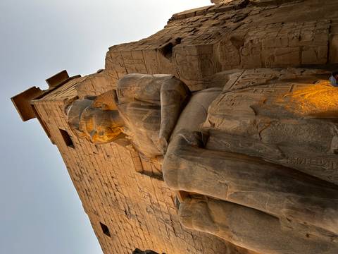       Statue of Ramses II sitting outside a temple at sunset
  