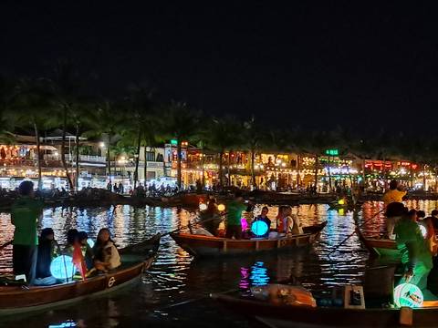 Night view of a brightly lit canal with boats and people