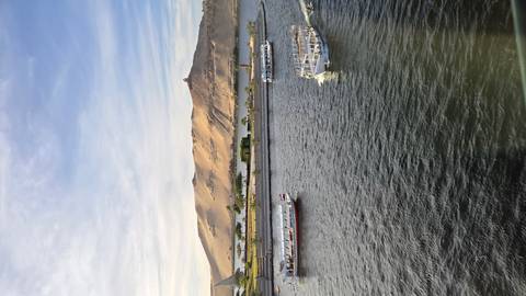 View of boats on the Nile River with desert hills in the background.