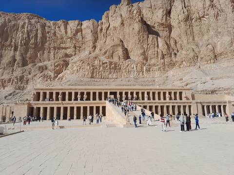       People visiting a large temple complex built into a cliff.
  