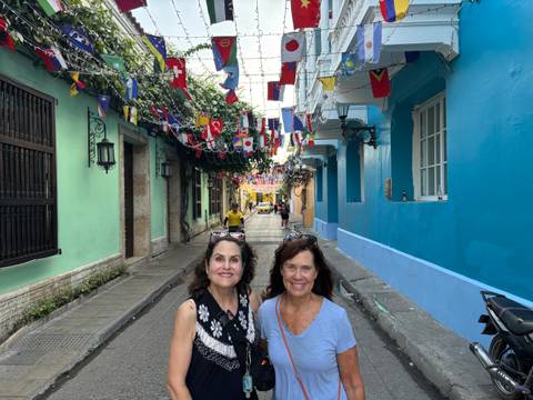 Two women in a colorful street with hanging flags.
