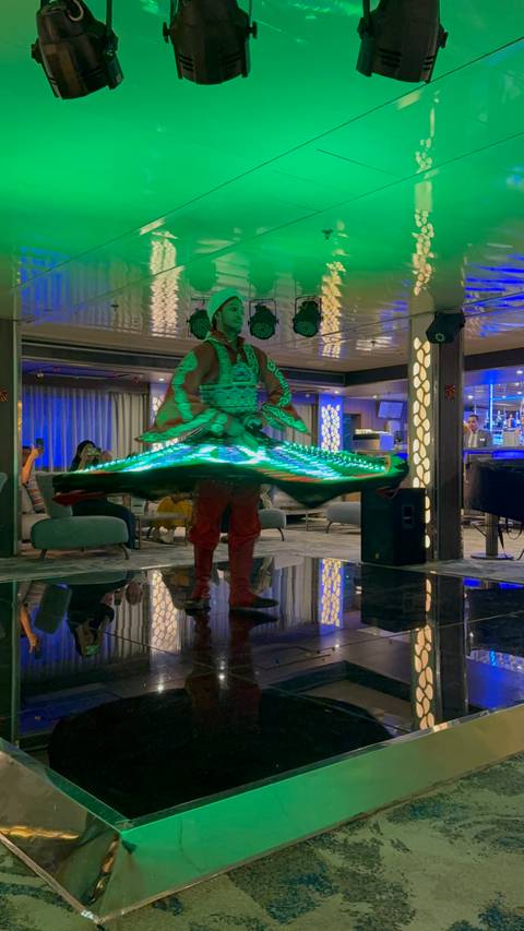A performer in an illuminated costume spinning indoors.
