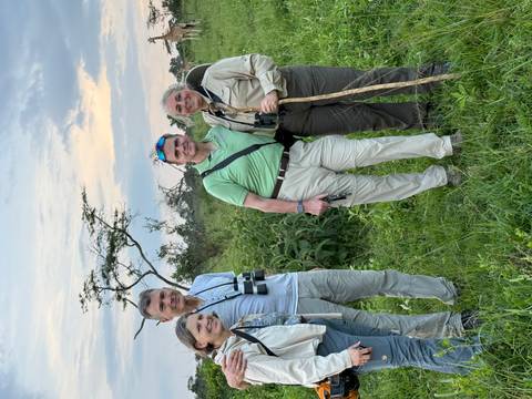 A group of people in safari gear standing in the wilderness