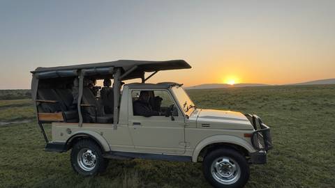       A safari vehicle with people inside during sunset
  