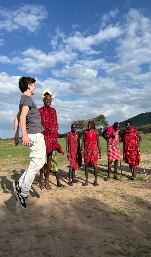       People jumping and posing with local tribe members
  