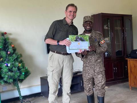 Two people smiling and holding a certificate indoors.