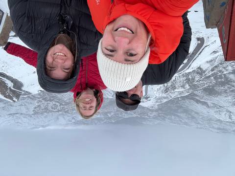 Four people posing on a snowy mountain with a panoramic view.