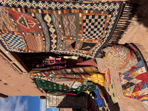       Colorful Moroccan carpets displayed outside a shop.
  