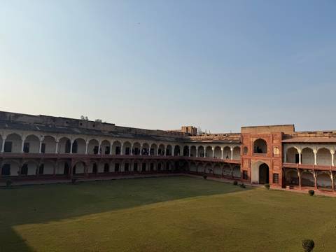 Historical courtyard with open green area and arcades.