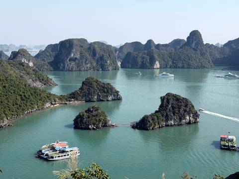 Panoramic view of karst formations and boats in the water under a blue sky.