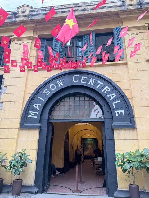       Entrance of Maison Centrale with red flags above.
  