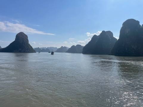       Karst landscape and calm water under a blue sky.
  