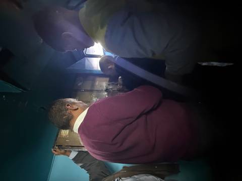 Group of people standing indoors in a dimly lit setting.