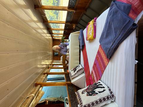 Person relaxing on a bed with colorful linens inside a boat.