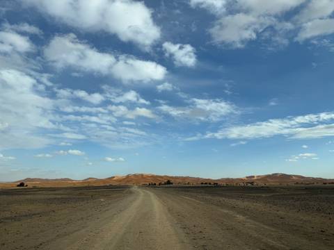       Dirt road leading to distant sand dunes.
  