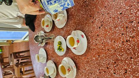 Pouring tea into cups set on a table.