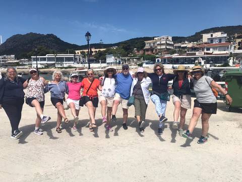       Group of people posing joyfully on a seaside area.
  