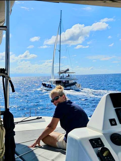       Person smiling on a sailing boat with another boat in view.
  