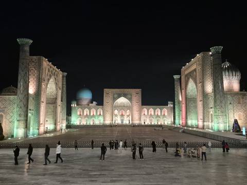 Registan Square with illuminated madrasahs and domes at night.
