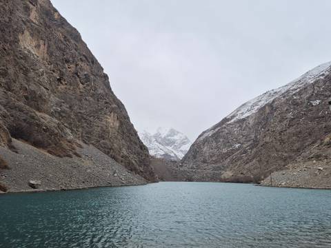       Serene lake surrounded by mountainous terrain and snow on peaks.
  