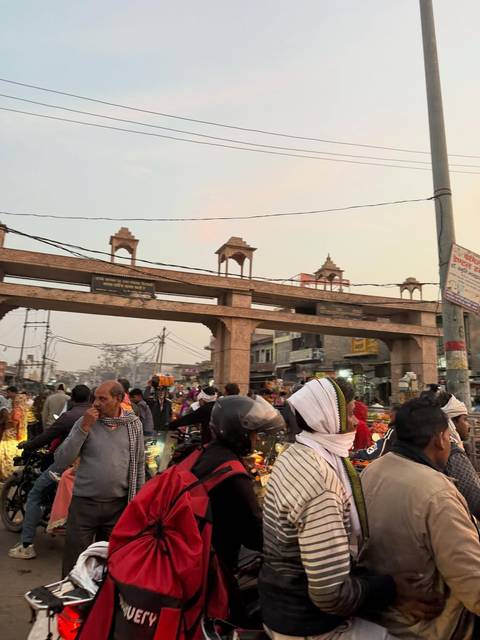 Busy street with people and traffic under a large archway.