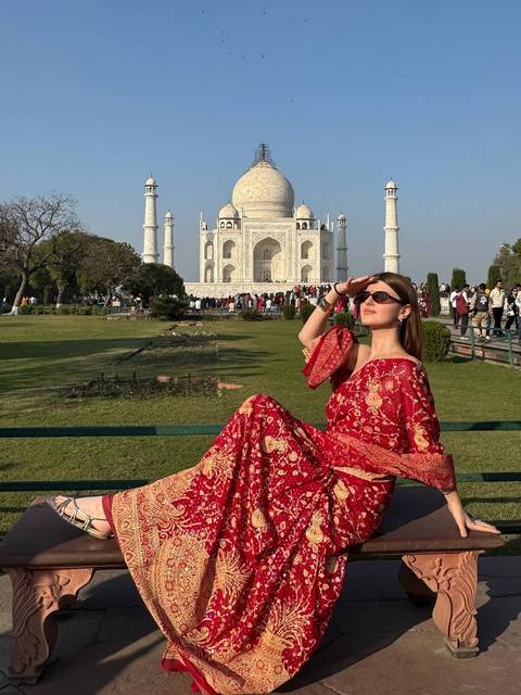       Woman posing on a bench in front of the Taj Mahal.
  