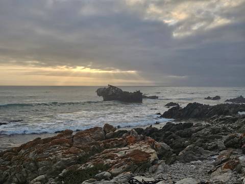       Scenic ocean view with a shipwreck and dramatic skies.
  