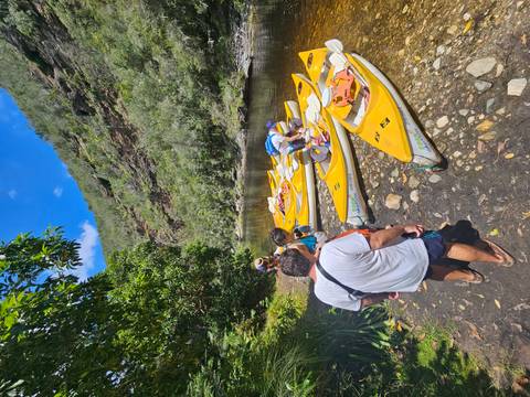       People preparing to kayak near a riverbank.
  
