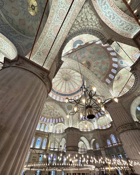       Detail of mosque interior with chandeliers and dome.
  