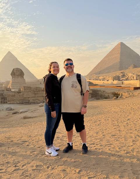       A couple posing in front of the Great Pyramid and the Sphinx.
  