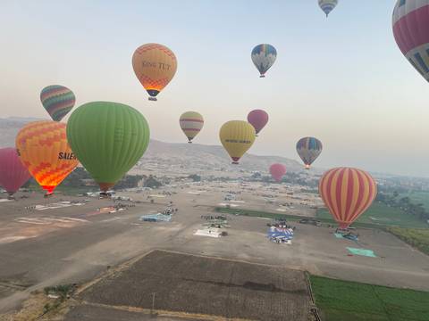 Hot air balloons floating over a desert landscape.