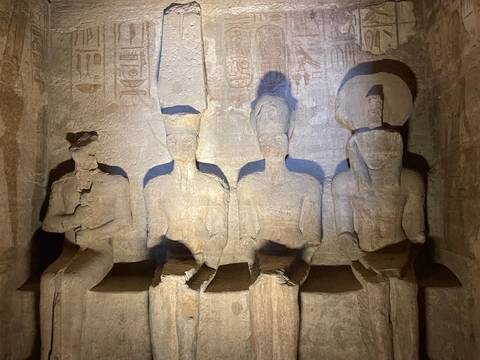 Four seated statues carved into a rock face.