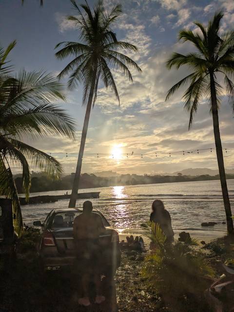 Sunrise or sunset over the ocean with silhouetted palm trees.