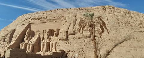       Rock-cut temple facade with statues in the desert.
  