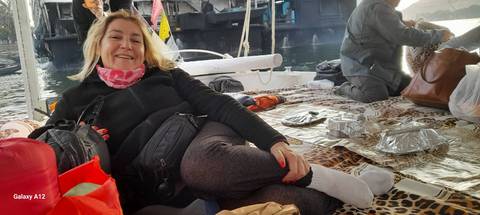 Woman relaxing on a boat with others in the background.