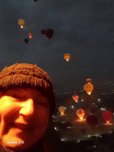       Hot air balloons in the dark sky with a smiling person.
  