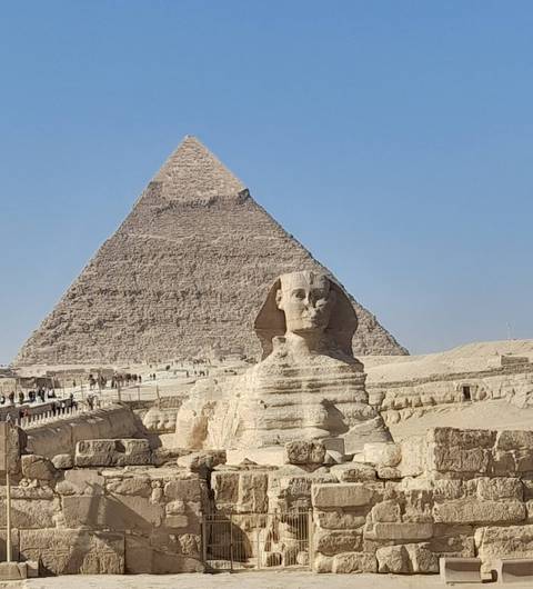 Sphinx statue with a large pyramid in the background.