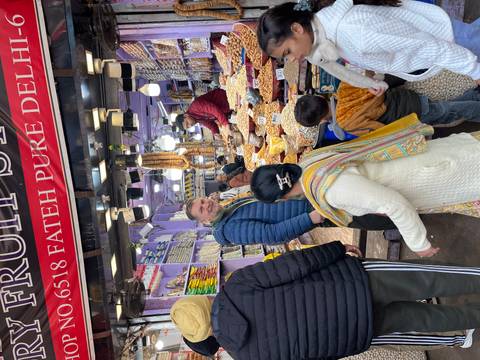 People shopping at a busy market stall with various goods.