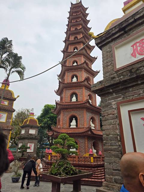       Brick pagoda tower with small white statues.
  