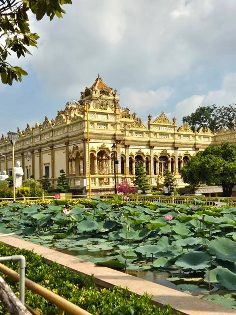       Ornate yellow temple with a lotus pond in front.
  