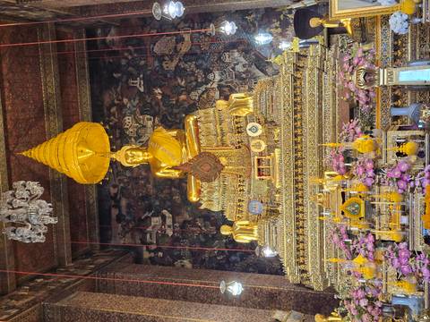 Golden sitting Buddha in a richly decorated temple.