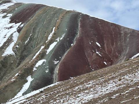       Colorful mountain slopes with patches of snow.
  