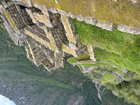Stone ruins with green moss on a steep hillside.