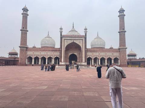Historic mosque with a courtyard and a person taking photos.