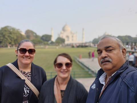 Three people posing with the Taj Mahal in the background.