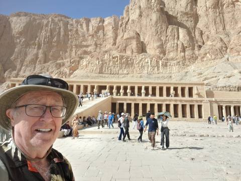 Man with hat in front of ancient temple with tourists.