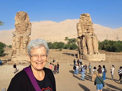 Statues of ancient Egyptian figures with tourists in the foreground.