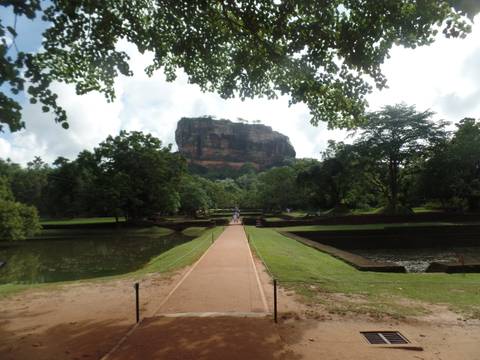 Pathway leading to Sigiriya rock surrounded by lush greenery.