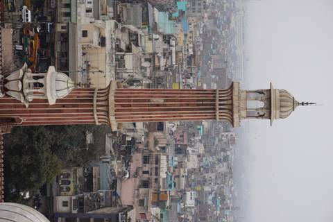 Tall minaret with a cityscape background.