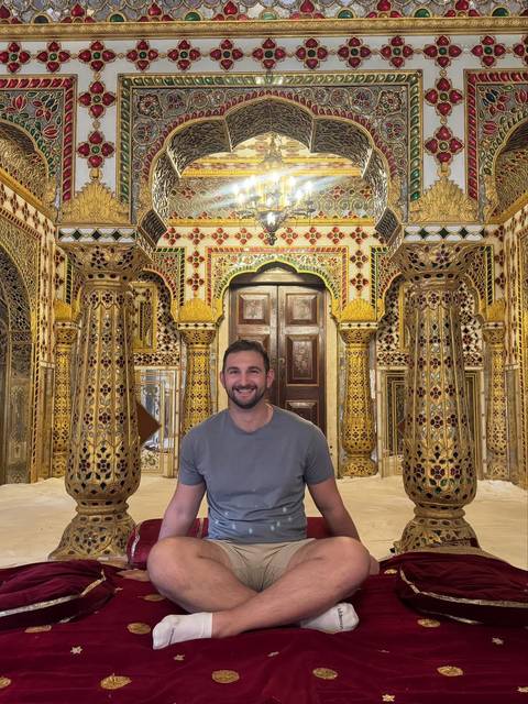       Man sitting inside a lavishly decorated room.
  